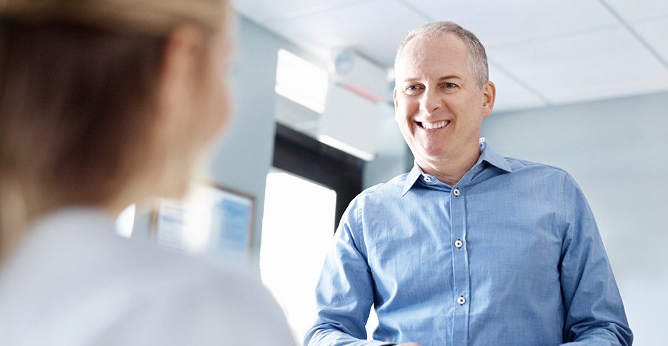 Smiling man turning in health insurance forms at reception desk