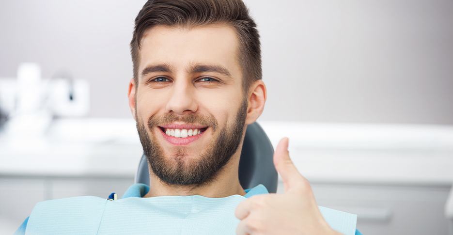 Smiling man in dental chair giving thumbs up