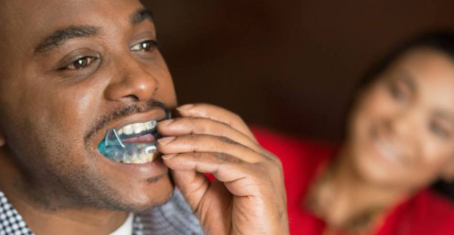 Man placing an oral appliance for sleep apnea therapy
