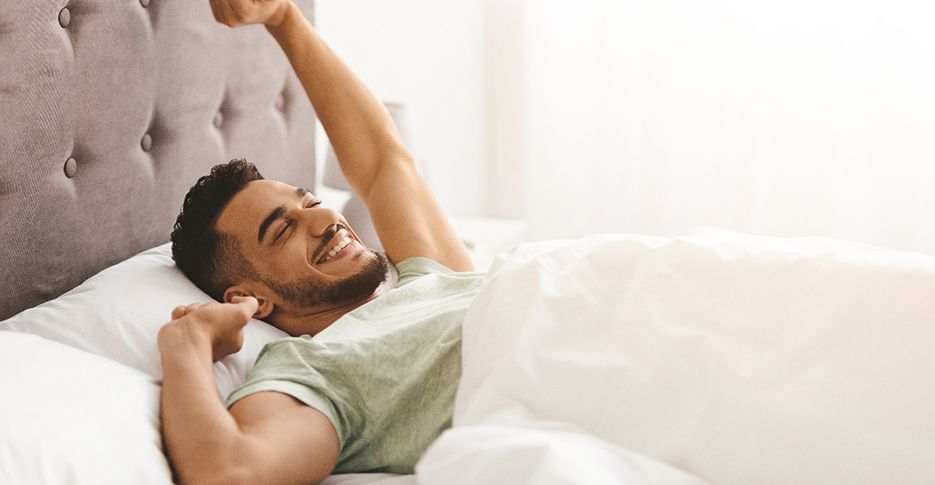 Man waking up refreshed after good night of sleep