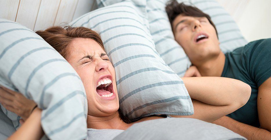 Frustrate woman next to snoring man in need of sleep apnea treatment