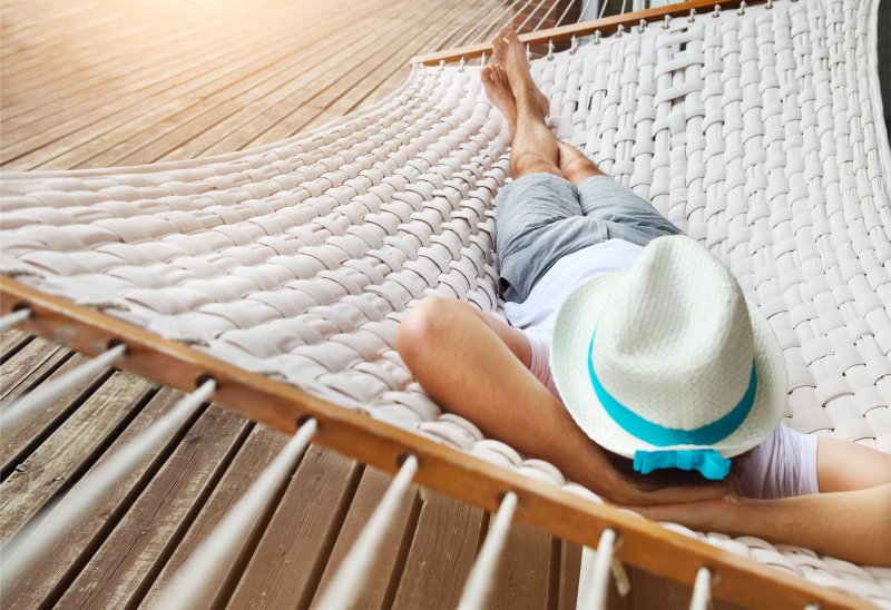 Man with hat sleeping on hammock during the summer