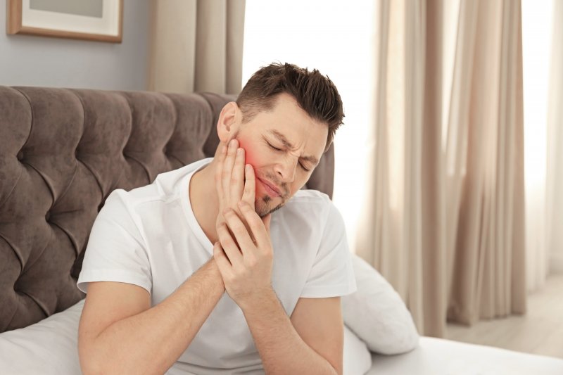 Man suffering jaw pain after waking up in bed