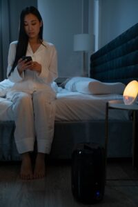 Woman sitting in bed looking at her cell phone